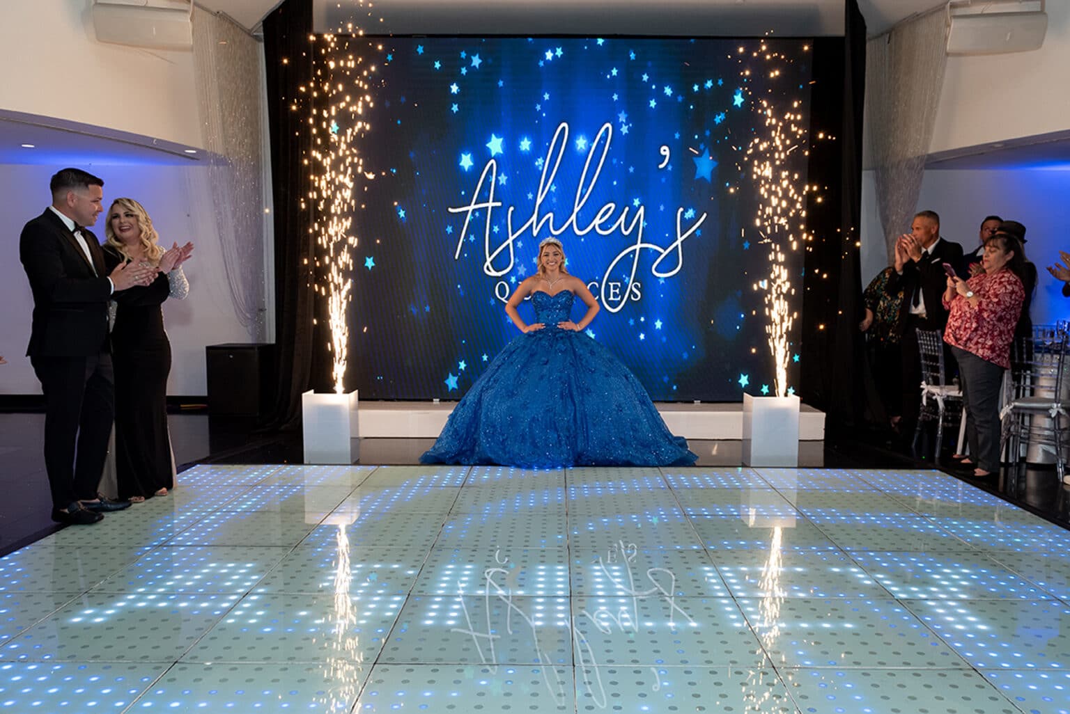 Ashley's Quinces at a Quinceañera Venue in Miami . Quinceañera with blue dress posing with fireworks